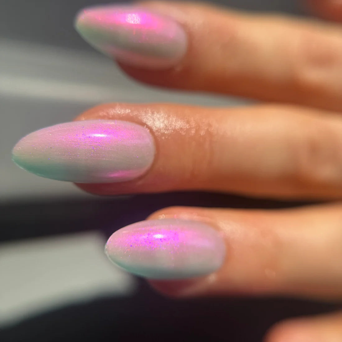 Close-up of a hand with pink and white marbled nail polish on a blurred background