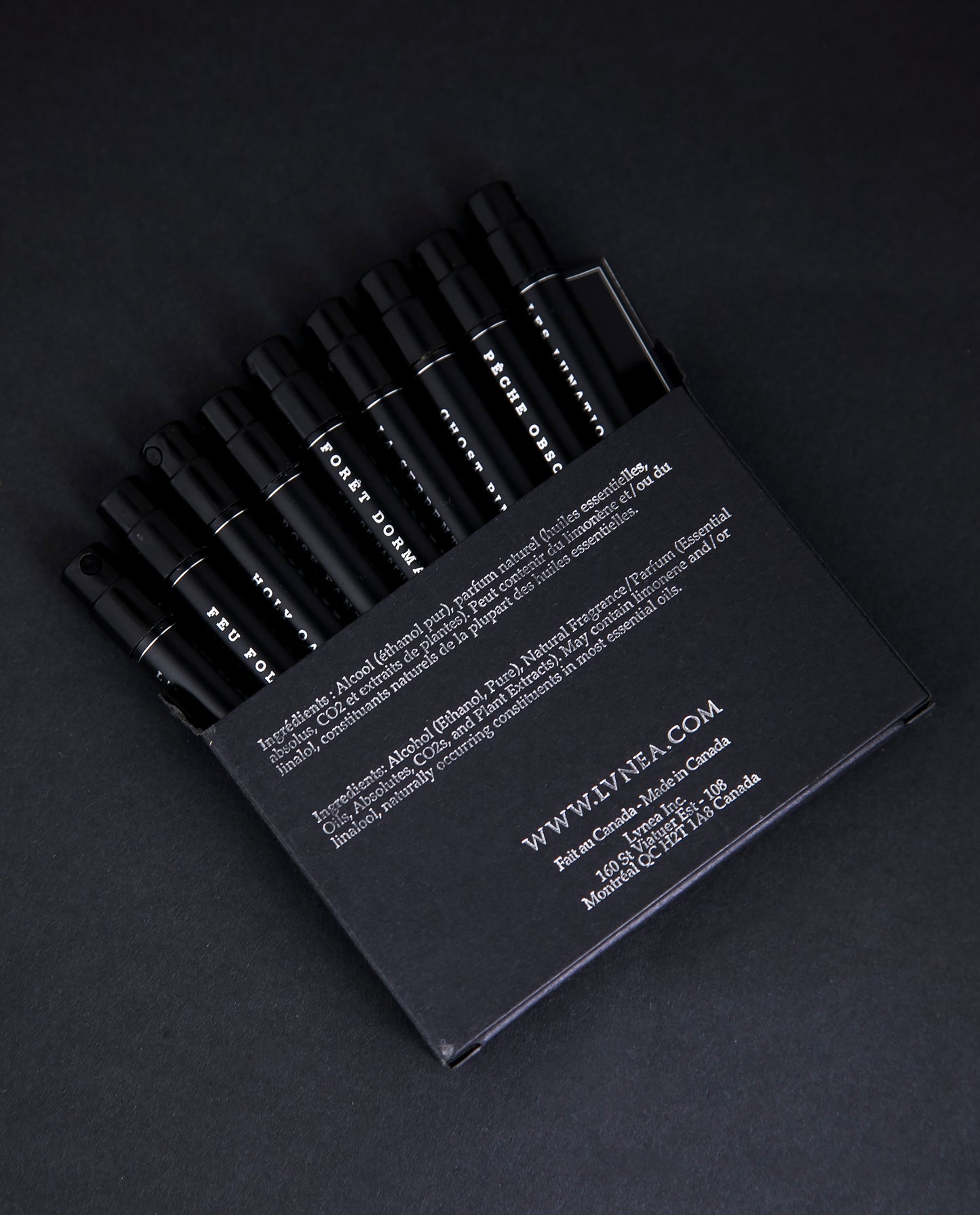 All 9 LVNEA eau de parfum samples peeking out from their black coardboard box, printed with silver foil