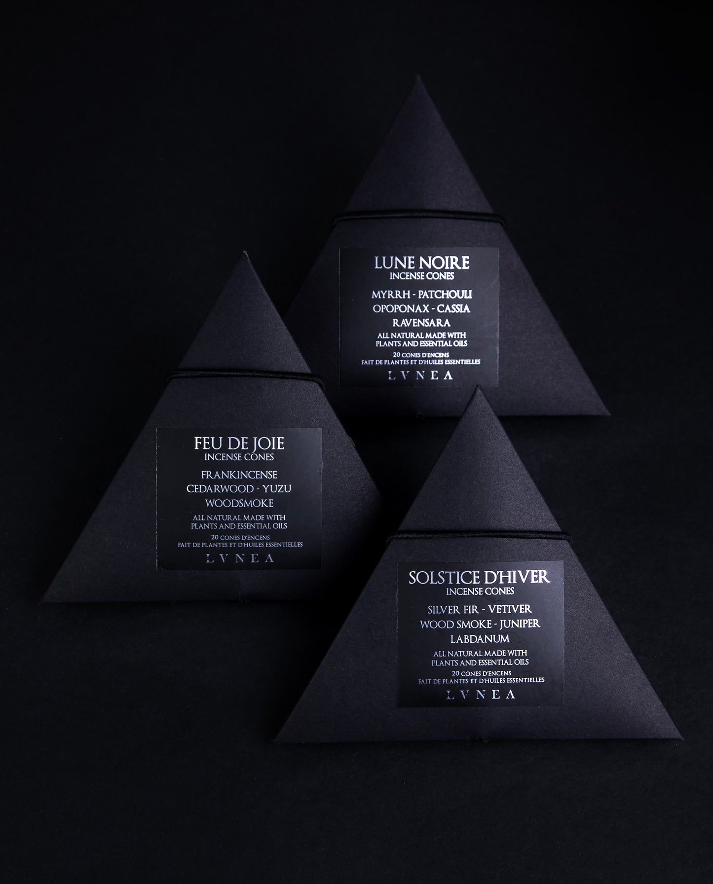 A set of three boxes of LVNEA incense cones. Each contains 20 cones housed in a recyclable black paper pyramid box with a black elastic closure. The labels are black with silver lettering each respectively describing the products as follows Solstice d'hiver features vetiver, woodsmoke, silver fir, labdanum, and juniper. Lune Noire myrrh, patchouli, opoponax, cassia and ravensara. Feu de joie features of frankincense, cedarwood, yuzu, and woodsmoke.