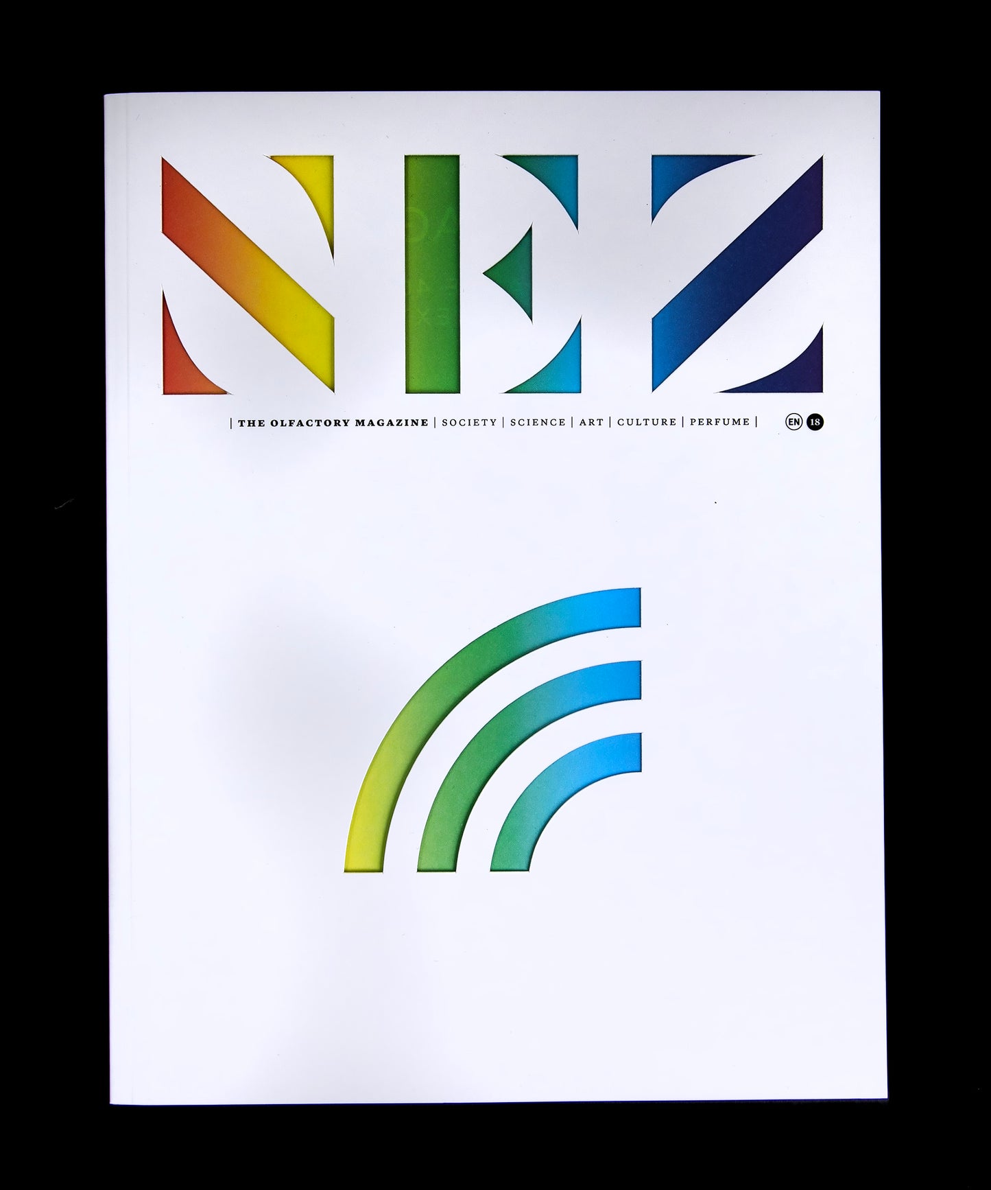 White magazine with rainbow cutouts reading