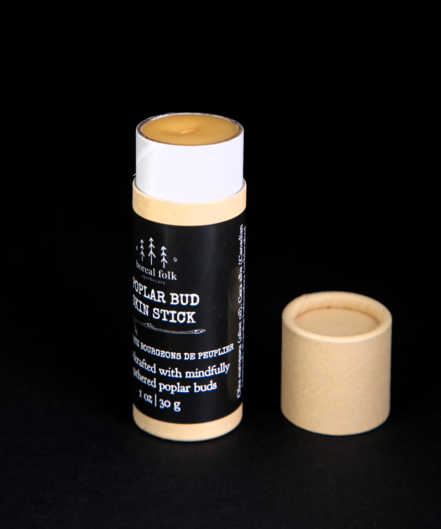 Poplar bud skin stick with its kraft cardboard lid removed, revealing the golden-hued balm within.