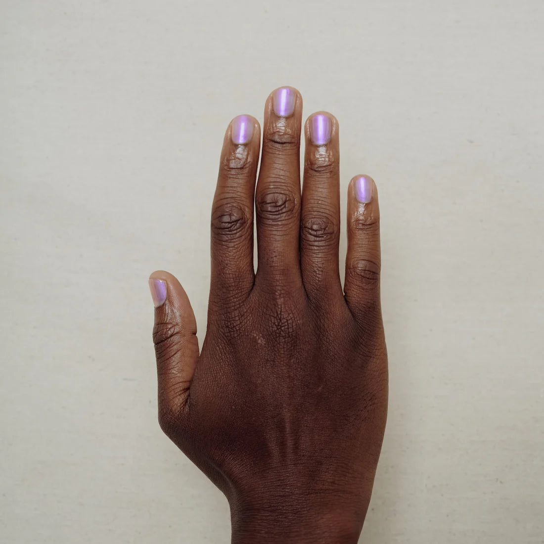 Hand with light purple nail polish on a plain background