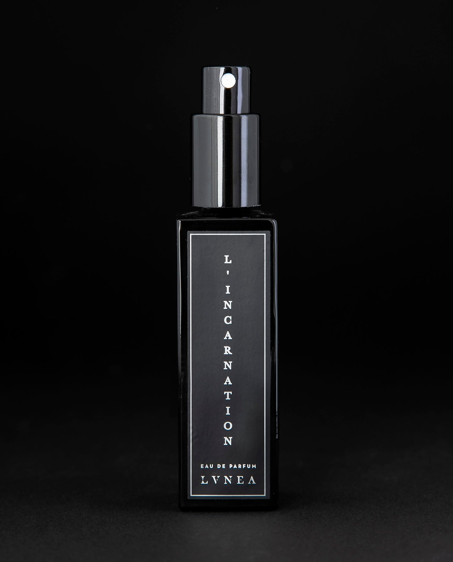 30ml black glass bottle of LVNEA’s L'Incarnation natural perfume on black background. The lid is removed, exposing the bottle's spray top.