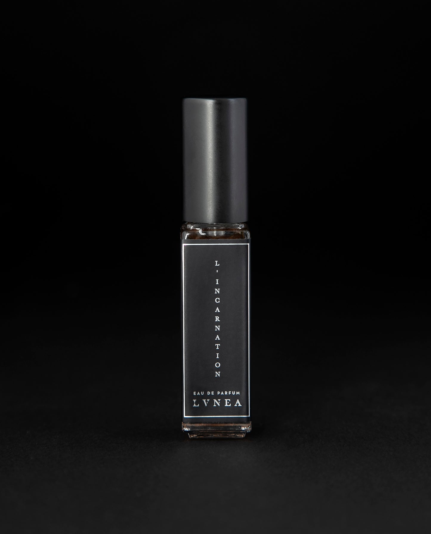 8ml clear glass bottle of LVNEA’s l'Incarnation natural perfume on black background