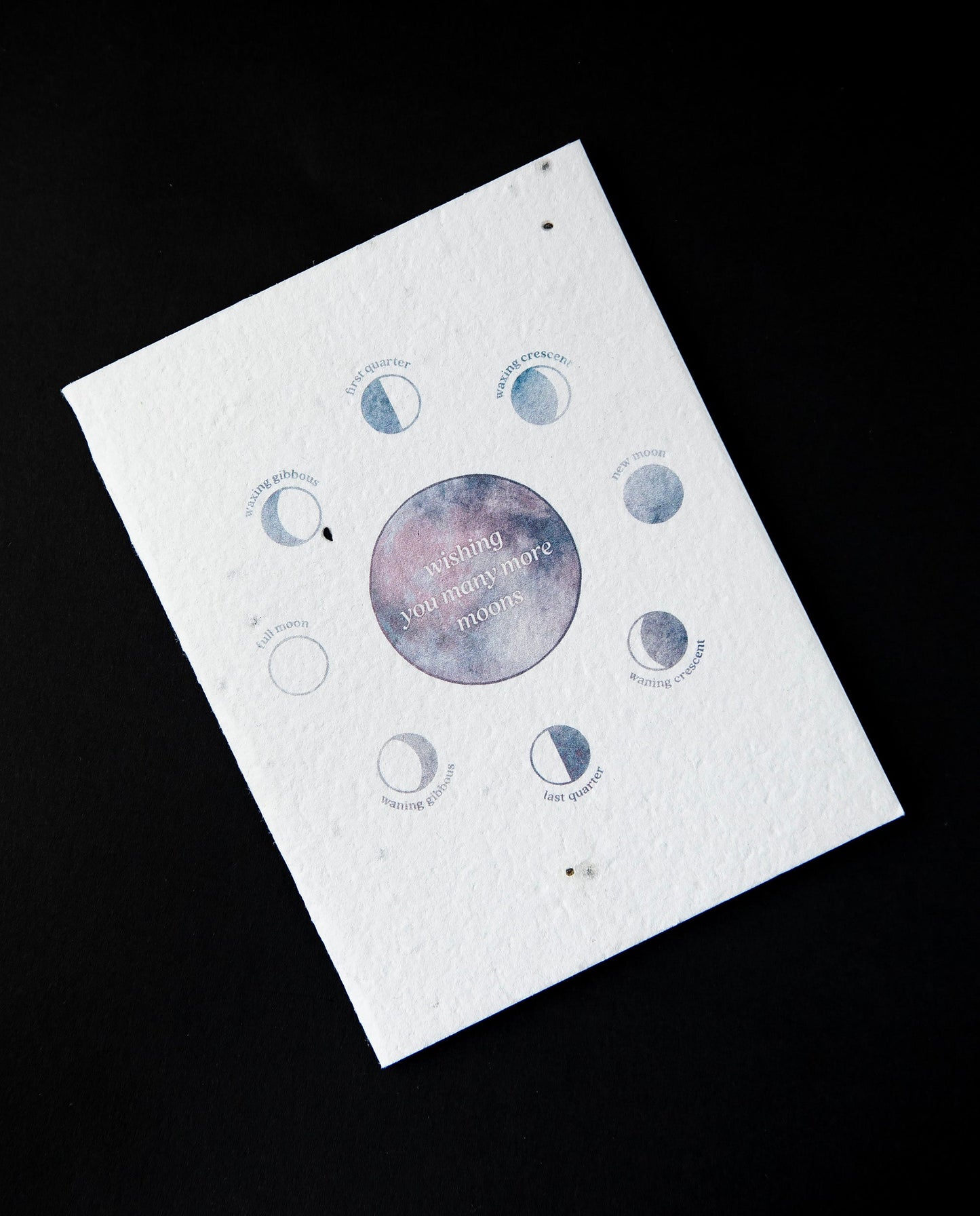 White greeting card featuring blue and purple watercolour illustrations of the moon's phases. The card reads