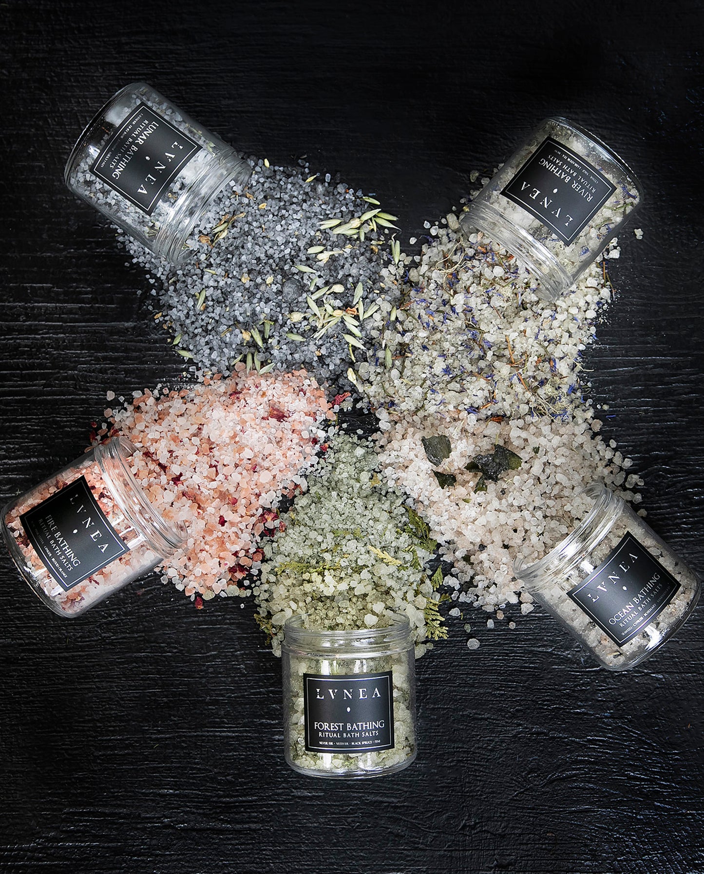 All five of natural perfumery brand LVNEA's elemental ritual bath salts arranged in a circle and spilling over with colourful salt blends.
