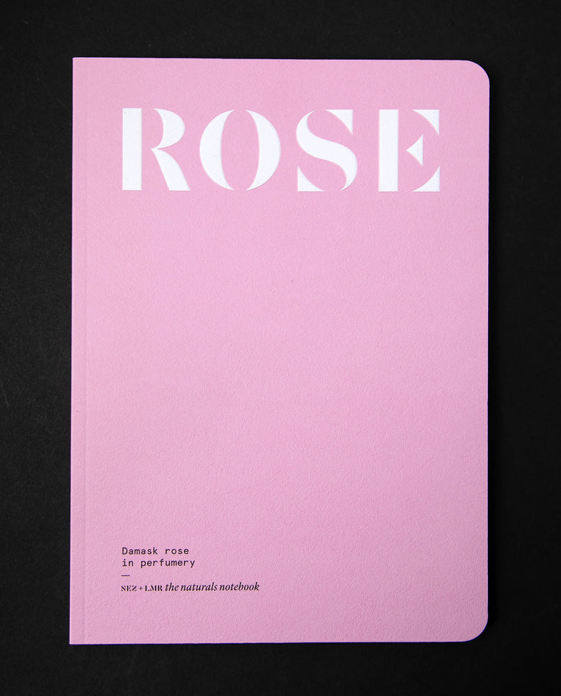 "Damask Rose in Perfumery" book on black background. The cover is flat pink and reads "ROSE" in a big bold font. 