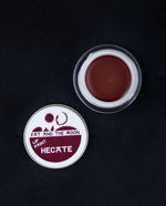 open glass pot of Fat and the Moon "Hecate" lip paint, revealing a deep wine red lip colour