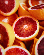 A sea of halved blood oranges piled on top of one another, their deep red flesh revealed.