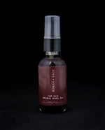 2oz glass bottle with pump top and burgundy label, containing Rowan + Sage's "The Sun" body oil on black background.