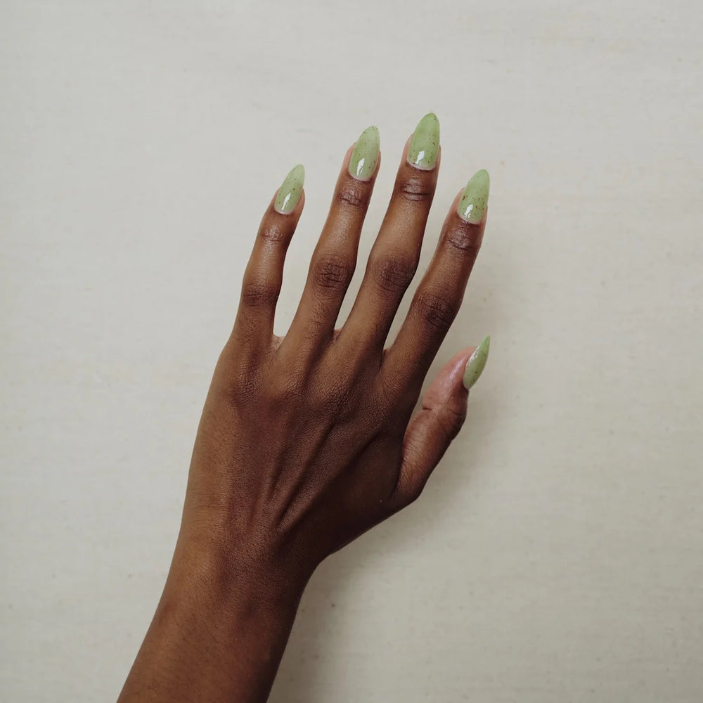 
                      
                        Hand with green nail polish on a plain background
                      
                    