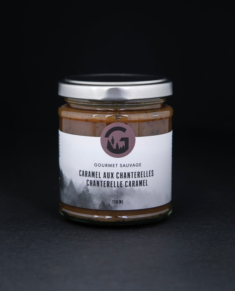 Clear glass jar with metal screw top lid containing chantelle caramel by "Gourmet Sauvage", sitting on black background