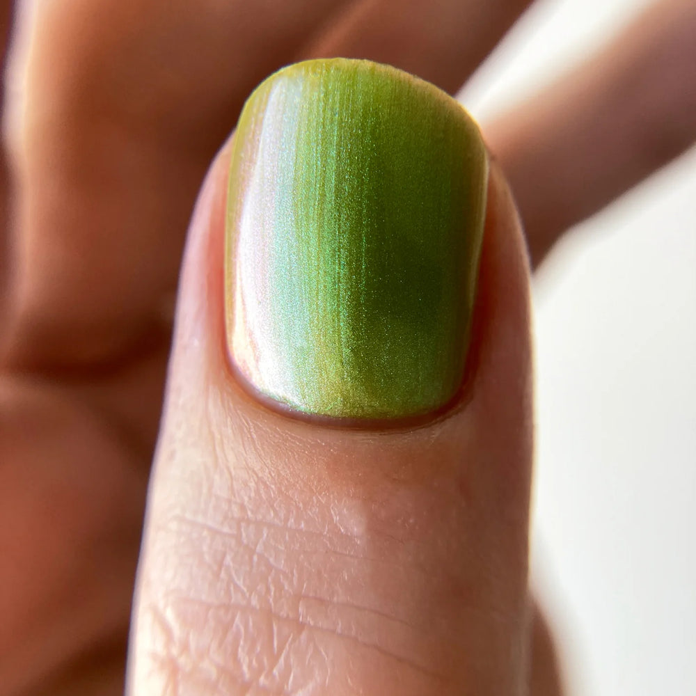 
                      
                        Close-up of a finger with green nail polish on a blurred background
                      
                    