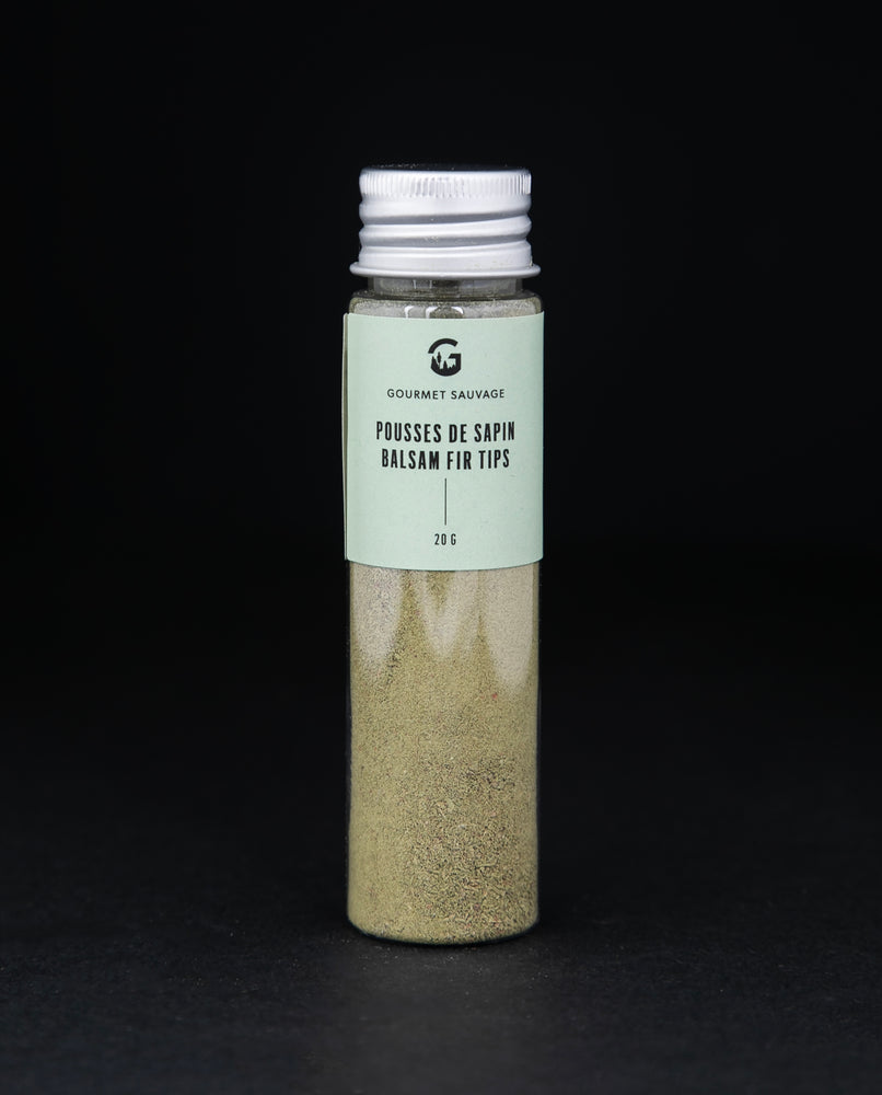 Clear tube of Gourmet Sauvage's balsam fir tip powder, sitting on black background. The powder is a vibrant green colour.
