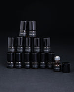 All 14 parfum botanique sample bottles stacked in a pyramid. One bottle is open, revealing the roller ball top.
