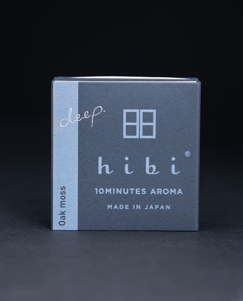 Dark slate grey paper box containing HIBI "oakmoss" incense matches, sitting on black background