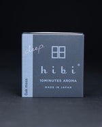 Dark slate grey paper box containing HIBI "oakmoss" incense matches, sitting on black background