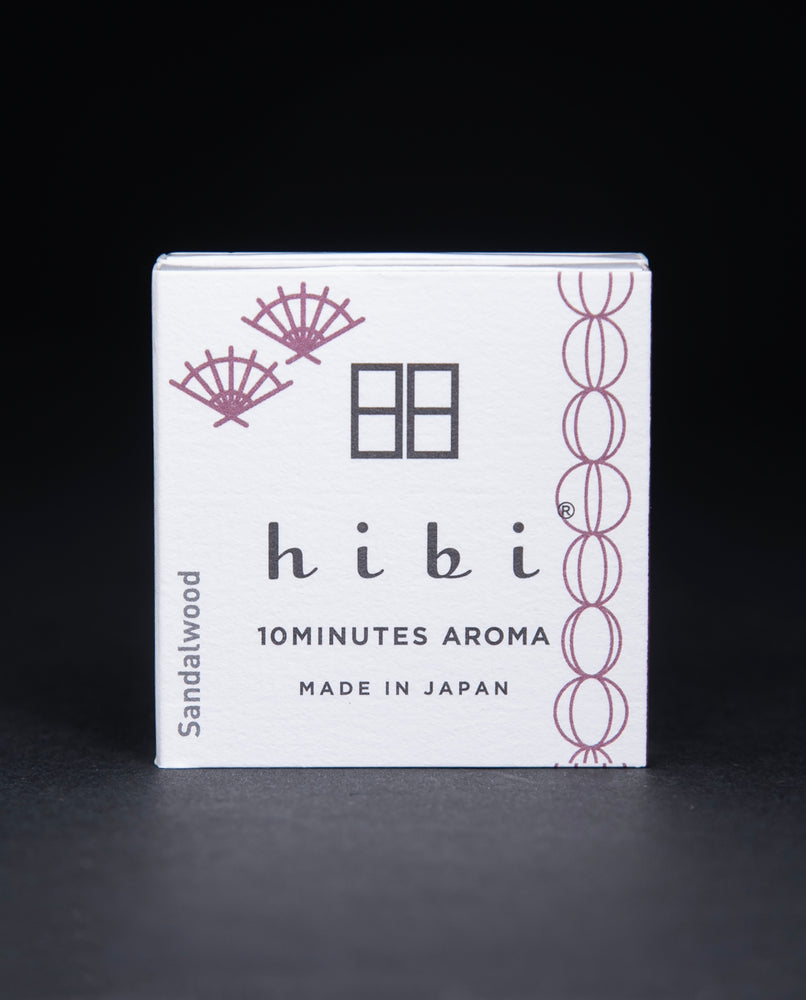 White paper box containing HIBI "sandalwood" incense matches on black background