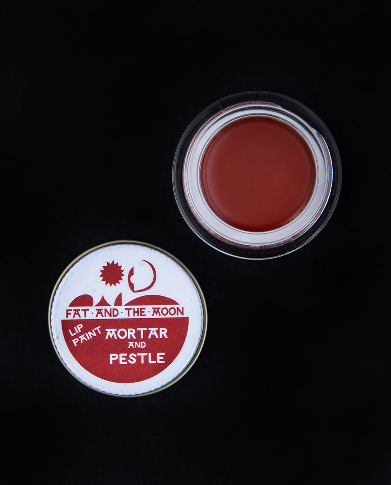 glass pot of Fat and the Moon "Mortar & Pestle" lip paint open, revealing a brick red lip colour