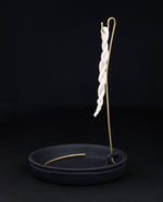 Rope incense holder with black ceramic base plate and brass hook on which to hang rope incense