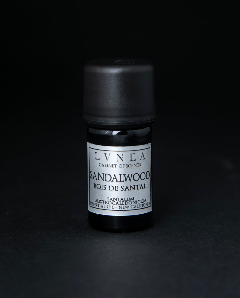 5ml black glass botttle of LVNEA's sandalwood essential oil on black background. The label on the bottle is silver.