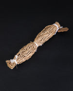 6 inch long bundle of vetiver root tied up with white twine, sitting on a black background
