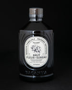 ornate black glass bottle of elderflower simple syrup on black background