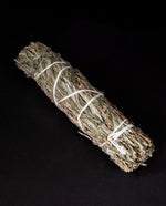 bundle of dried mugwort wrapped in white string on black background.