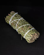 bundle of dried rosemary wrapped in white string on black background.