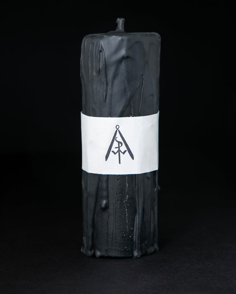 Tall black beeswax pillar candle by RITUAALIA on black background. The candle has a rustic textured finish with visible drips.