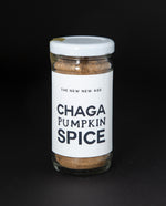 Clear glass jar of The New New Age's "Chaga Pumpkin Spice" herbal blend on black background.