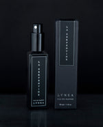 30ml black glass bottle of La Serpentine natural perfume sitting next to the black box it comes packaged in