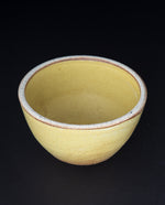 light yellow stoneware bowl on black background