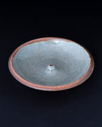 cream coloured glazed stoneware incense holder on black background