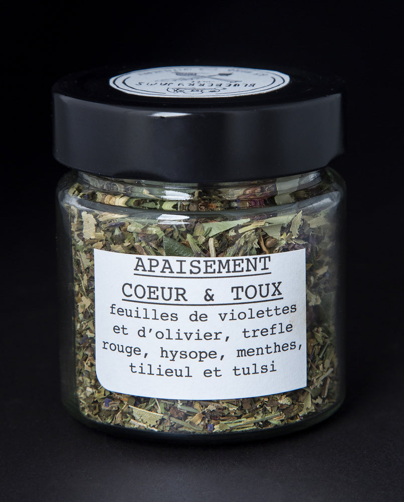 Clear glass jar with black lid containing a herbal tea blend by blueberryjams. The jar is rotated to showcase the french label side which reads "Apaisment Coeur et Toux"