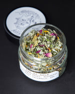 Open glass jar revealing the dried herbal rolling blend within.
