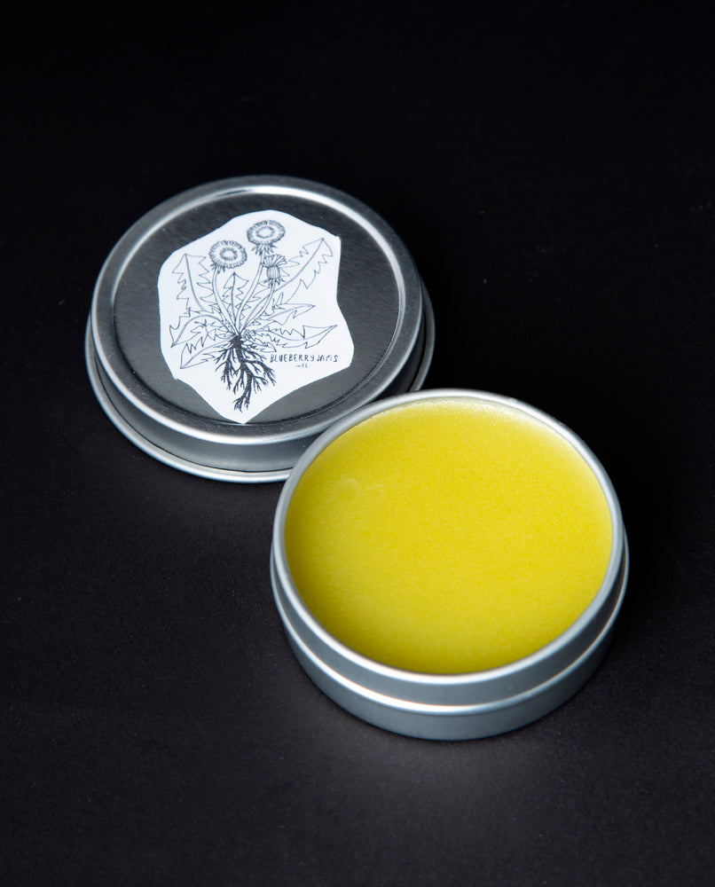 open metal tin of blueberryjams' "Flying Ointment", revealing a bright yellow herbal salve