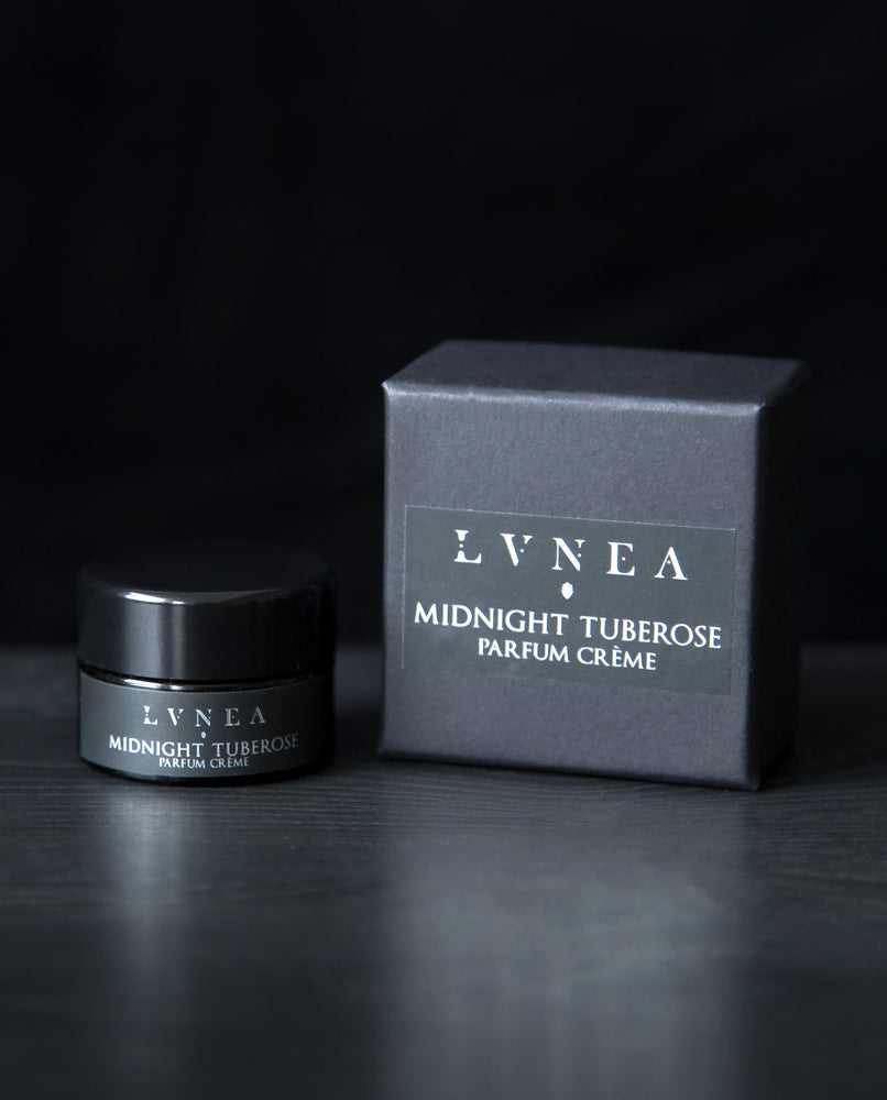 A dark, indolic floral vegan solid perfume by natural and botanical fragrance brand LVNEA with notes of tuberose, rose, sandalwood, resins, cacao, and cepes. Presented in a 10g black glass pot, the label reads MIDNIGHT TUBEROSE.