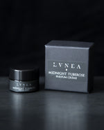 10g black glass jar of LVNEA's Midnight Tuberose solid perfume next to its box on black background