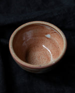 speckled rust-coloured stoneware bowl on black background