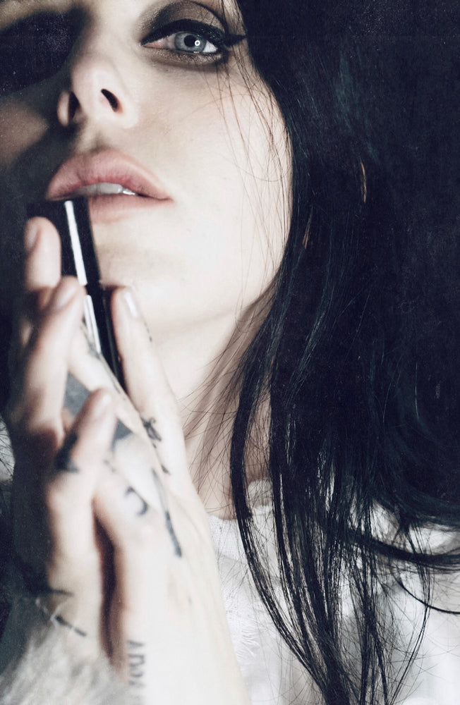 Singer songwriter Chelsea Wolfe cradles a bottle of her collaborative fragrance with natural and botanical perfume brand LVNEA, Pêche Obscène.