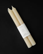 Cream coloured set of beeswax tapers on black background