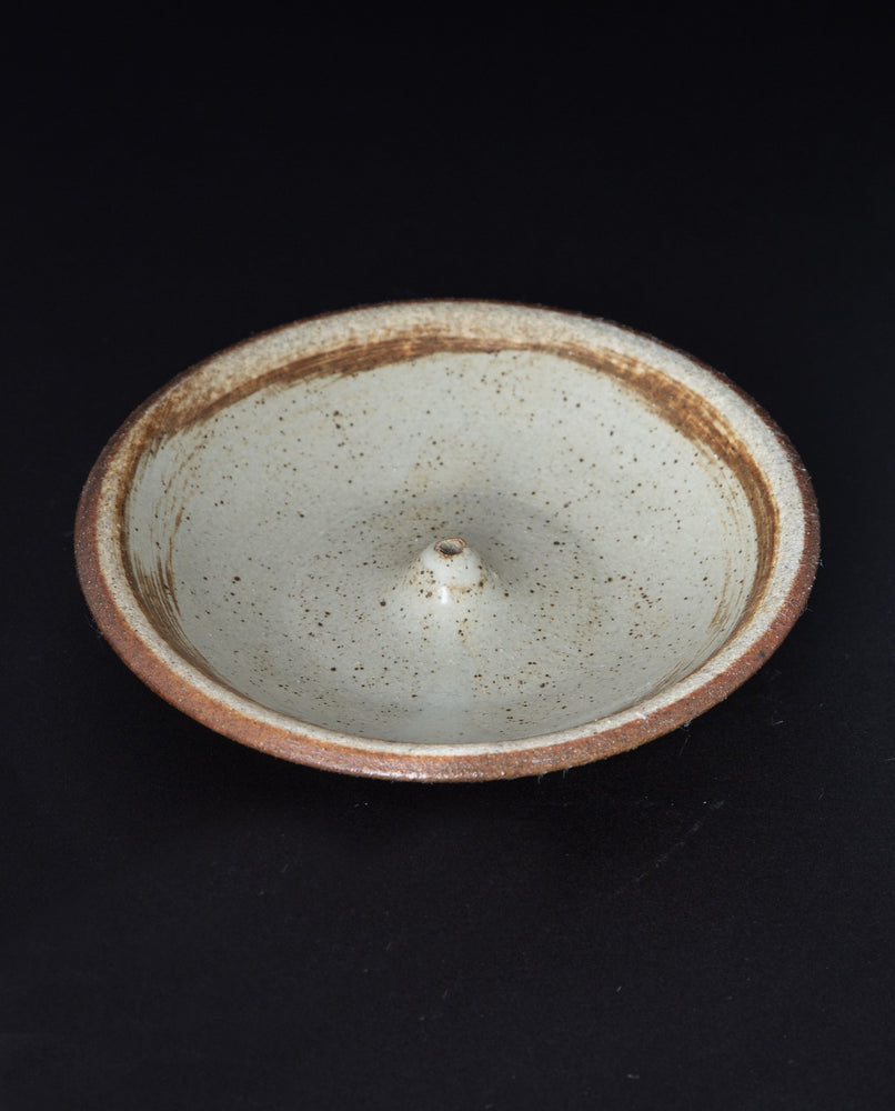 cream coloured glazed stoneware incense holder on black background