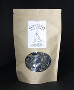 Brown resealable bag containing butterfly pea flowers. There is a clear window in the bag exposing the loose leaf tea. 