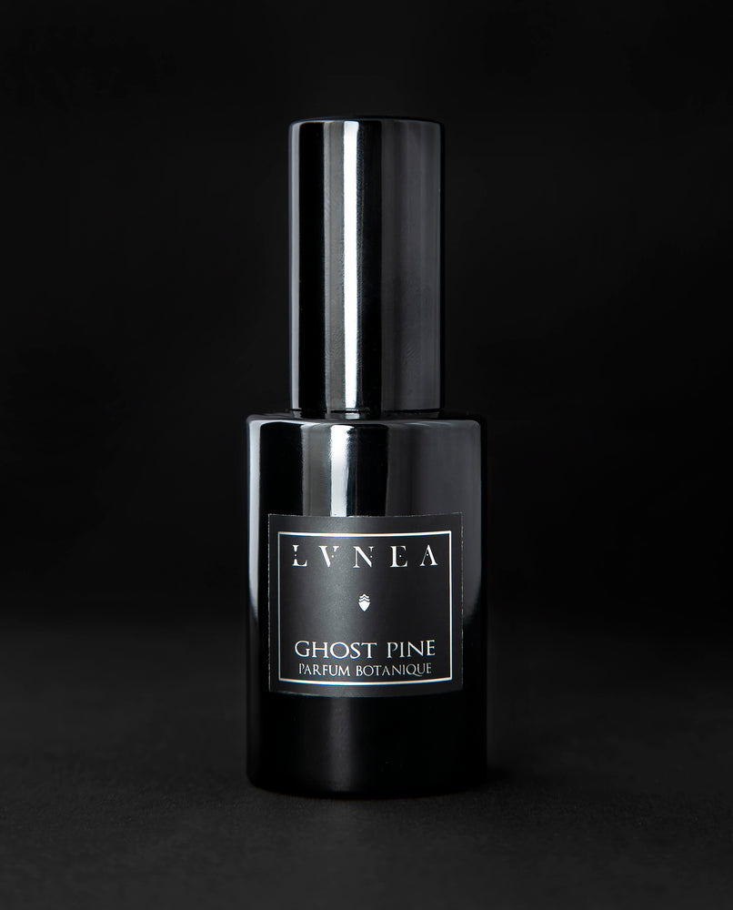 A bright, green, best selling unisex forest fragrance by natural and botanical perfume brand LVNEA with notes of crisp pine needles, dense conifers and foliage, ancient woods, damp earth, and fog. Presented in a 30ml black glass bottle, the label reads GHOST PINE EAU DE PARFUM. 