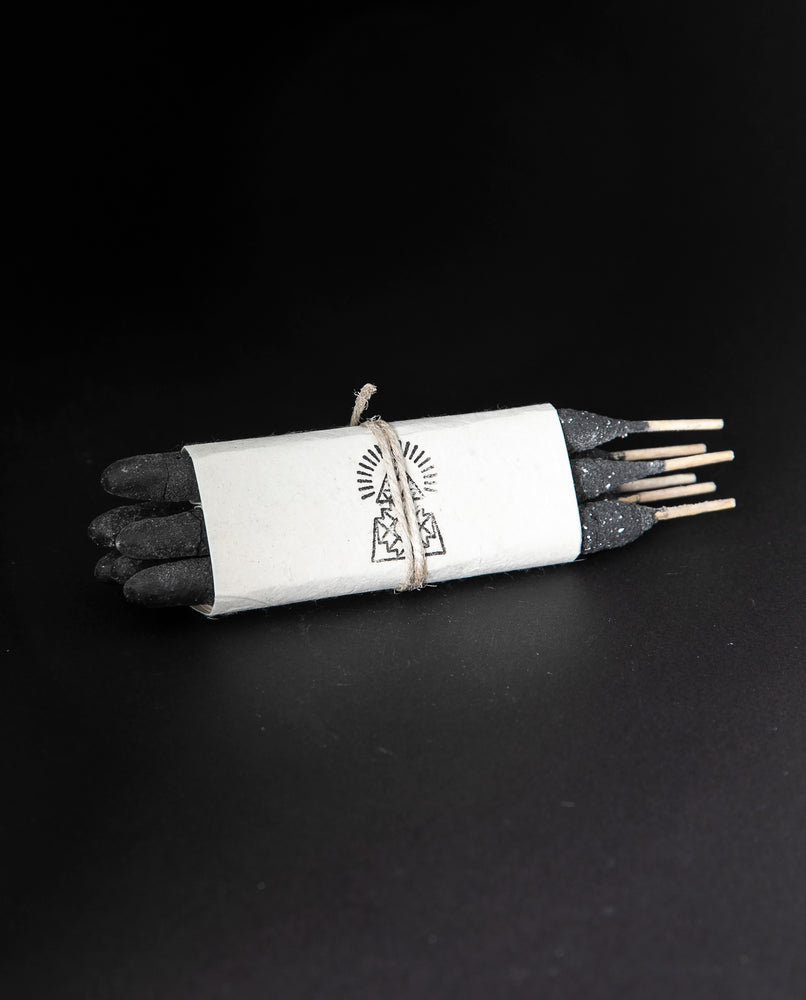one bundle of Incausa's hand-rolled pure breu incense wrapped in white paper and twine, on a black background