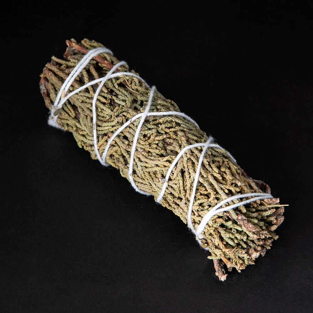 
                      
                        bundle of dried juniper wrapped in white string on black background.
                      
                    