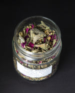 Clear glass jar with lid removed, revealing a herbal tea blend.