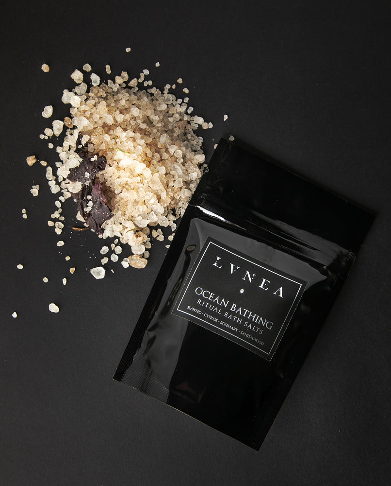 4oz black resealable pouch of LVNEA's Ocean Bathing bath salts with a mound of clay-hued and seaweed-speckled salt next to it