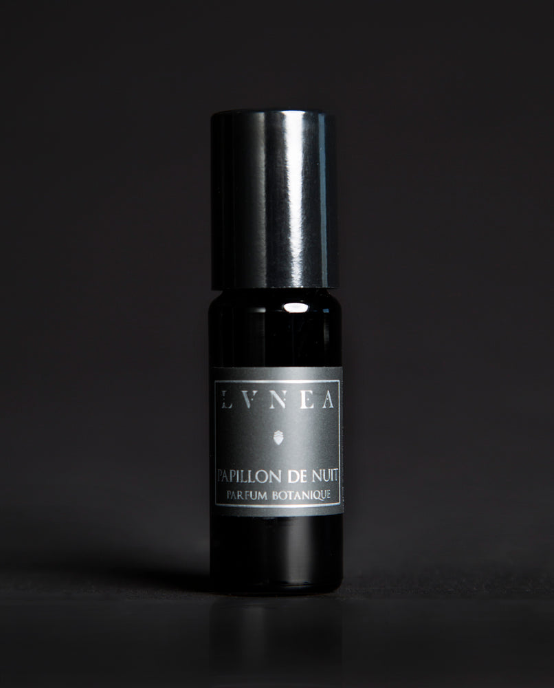 10ml black glass bottle of LVNEA's Papillon de Nuit natural roll on perfume oil on black background